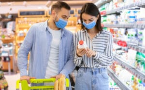 young couple in face masks shopping in supermarket T5GXKWA scaled e1607969084942